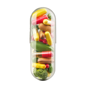 Transparent pill is standing filled with a variety of colorful vitamins and supplements, suggesting a concept of natural medicine